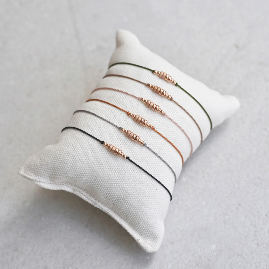 simple silk cord bracelet adorned with smooth and shimmery textured 14k rose gold-filled beadS, ON PILLOW