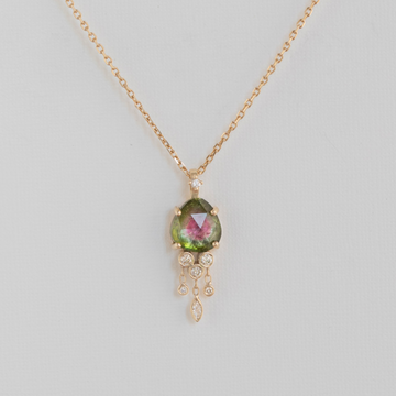 pink and green watermelon tourmaline prong set in 14k gold with small white diamonds dangling from it, all on a delicate 18 inch chain