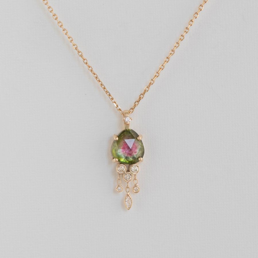 pink and green watermelon tourmaline prong set in 14k gold with small white diamonds dangling from it, all on a delicate 18 inch chain