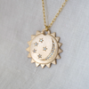 3 of 3: Gold medallion with serrated edges and diamonds on linen background