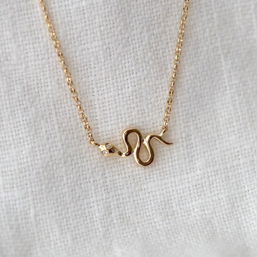 A tiny gold snake with diamond eyes on delicate gold chain