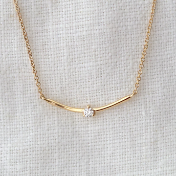 Gold arched bar with a white diamond set in the center