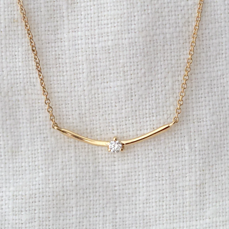 Gold arched bar with a white diamond set in the center