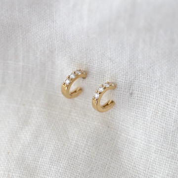 These classic wide 14k gold huggie hoops feature 4 white diamonds set along their curve