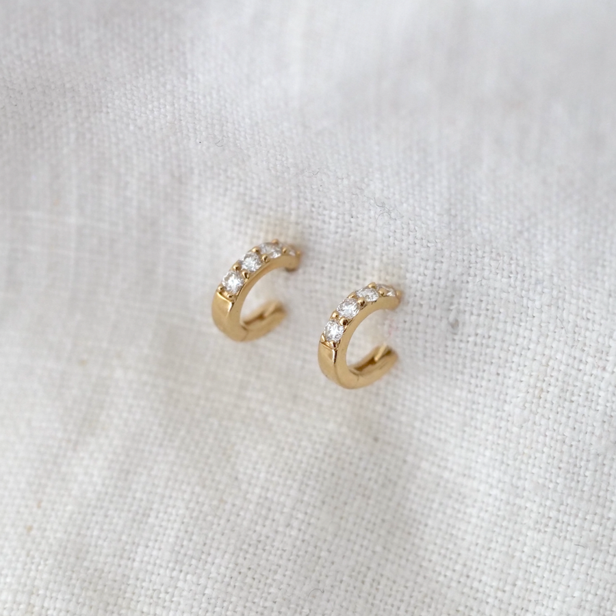 These classic wide 14k gold huggie hoops feature 4 white diamonds set along their curve