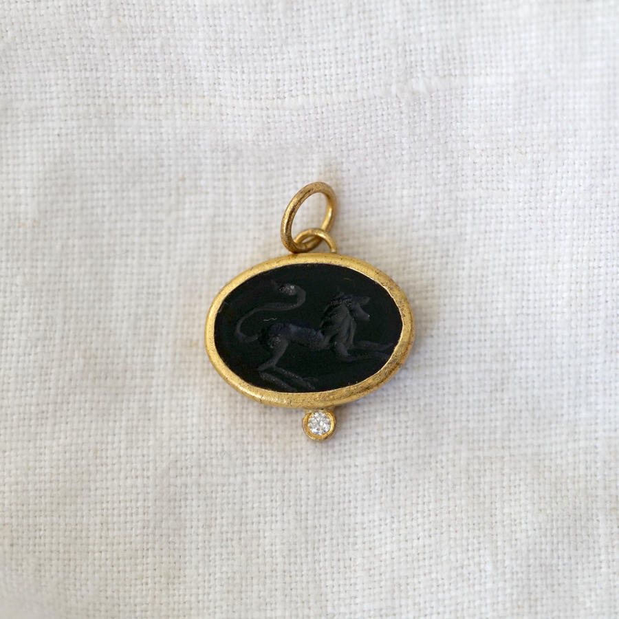 lion carved intaglio into a piece of black onyx, with a 24k gold frame and a white diamond adorning the base