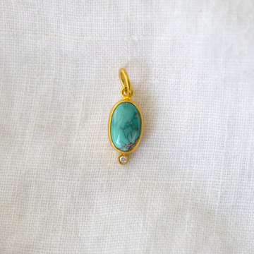 oval pendant of variegated turquoise, framed in rich 24k gold with a white diamond set at the base