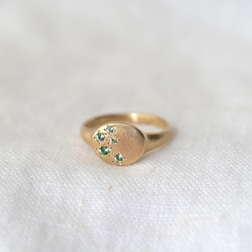 star-set green sapphires of varying tones on 14KY gold round signet ring