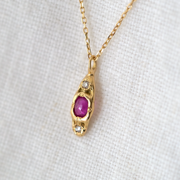 14k gold oblong pendant set with one oval ruby and two small white diamonds