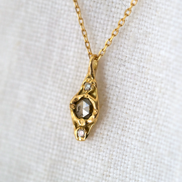 14k gold oblong pendant set with one rose cut round grey diamond and two small white diamonds