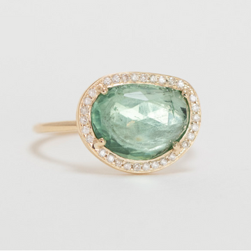 14k light yellow gold ring with a blue tourmaline surrounded by diamonds.