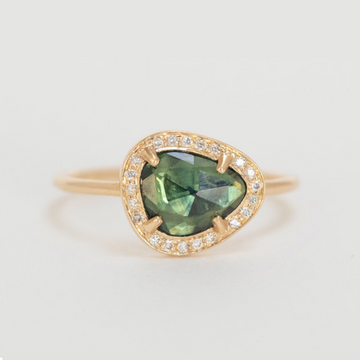 gold ring with a green sapphire surrounded by diamonds. The stone comes in a gradient of light green.