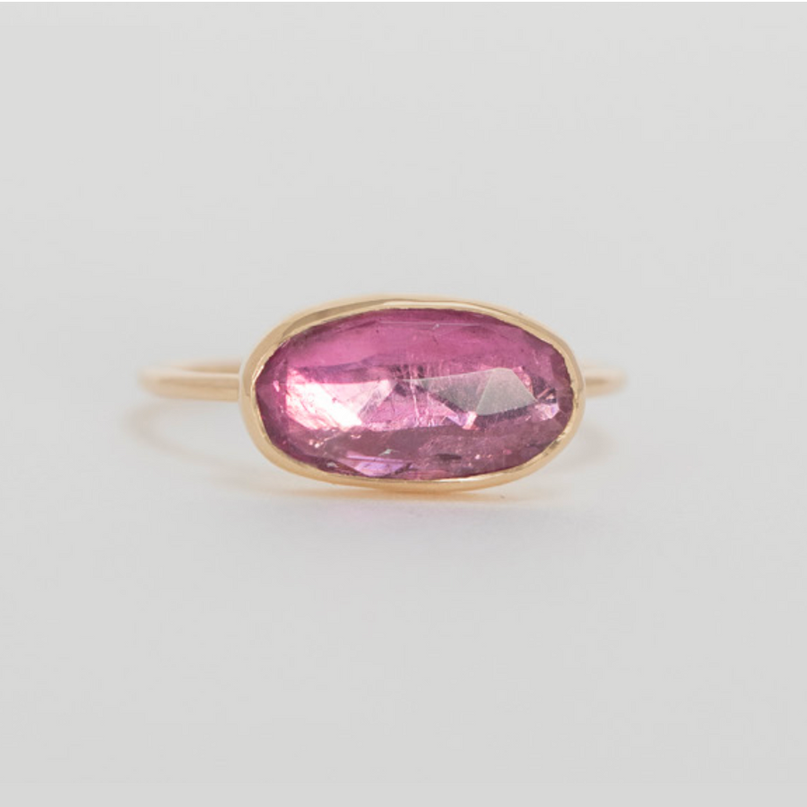 A beautiful light pink tourmaline oval sits in a delicate 14k yellow gold bezel setting