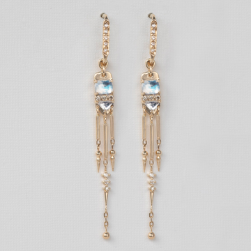 A pair of long dangling earrings featuring white diamonds set in gold, with iridescent moonstones and an articulated golden fringe hanging below.