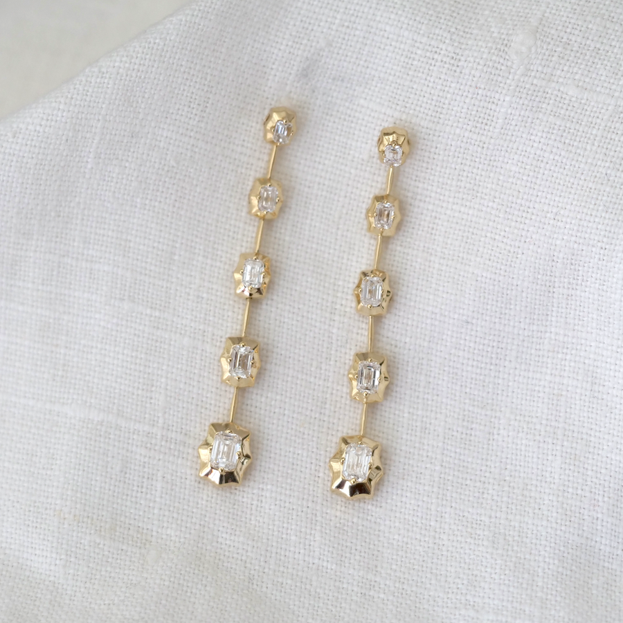five white emerald cut diamonds, set in sparkling high polished 14k gold in star shaped settings