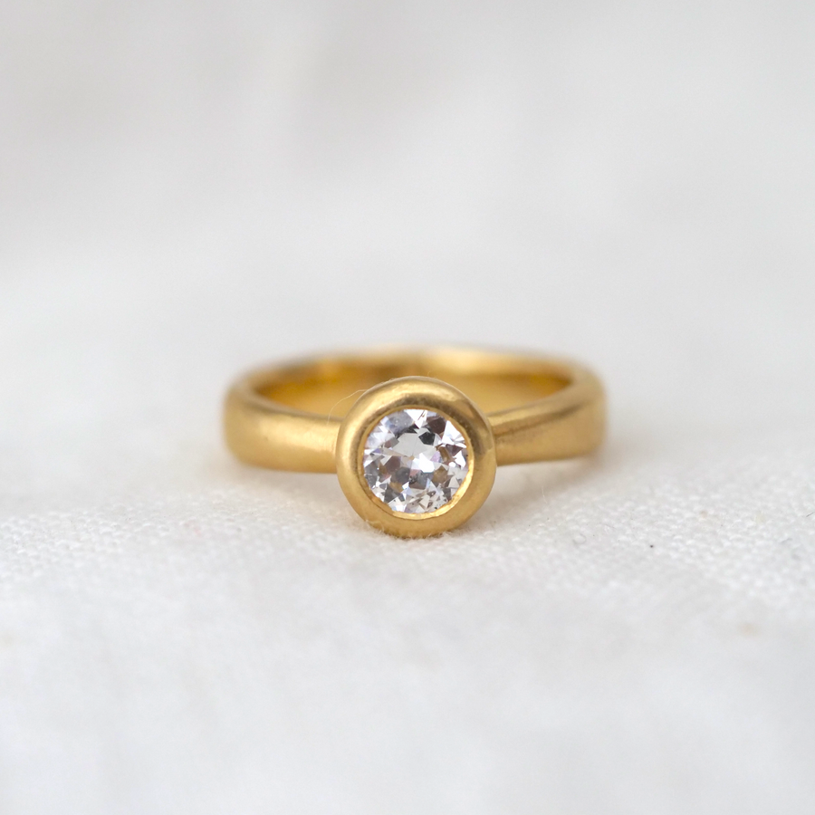 sparkling Old European Cut vintage diamond is bezel set in a hand-carved 18K gold band that tappers under the stone