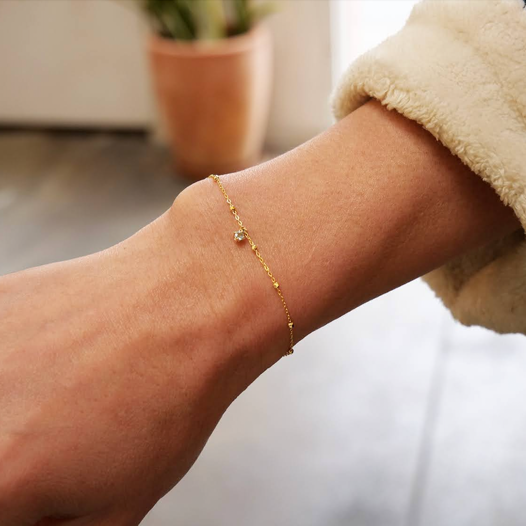 wrist with gold bracelet with charm