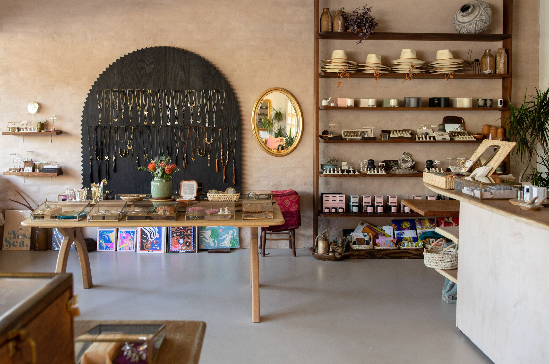 Interior of Santa Barbara store with selves of product, table with products, front check out counter, wall with necklace 