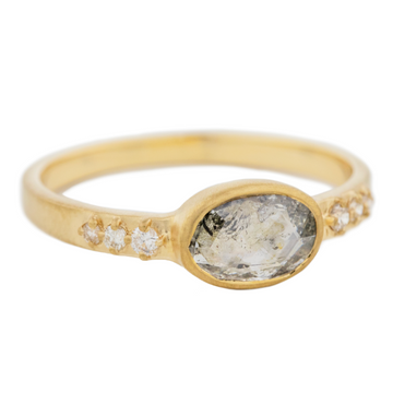 Simple and elegant oval rose cut grey diamond set in 14k yellow gold with 3 small white diamonds on either side.