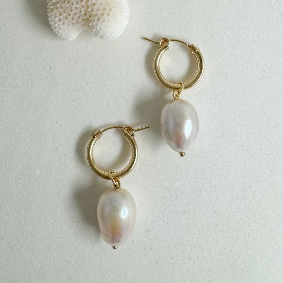 Twin baroque pearls hang from modern gold hoops