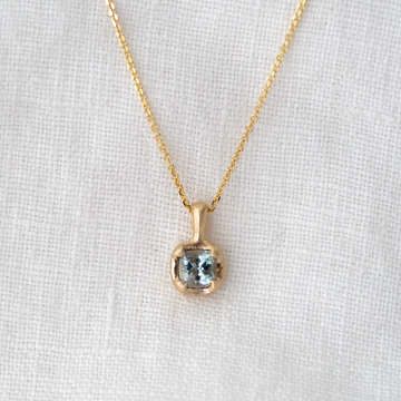 light blue montana sapphire set in gold on gold chain and white background