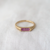 A slim rounded gold band with a signet like face made of a beautiful pink sapphire bar