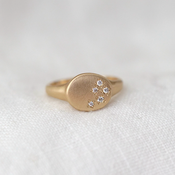 gold oval signet ring with five white diamonds star set in a scattered pattern on the face 