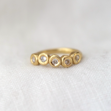 five vintage white diamonds bezel set in an 18k gold curved band