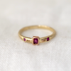 baguette ruby sits perfectly bezel set in 14k Rose Gold on a 14k Yellow Gold band, in between two gold rock sediment specs hand carved in 14k Rose Gold, and two flush set princess cut rubies