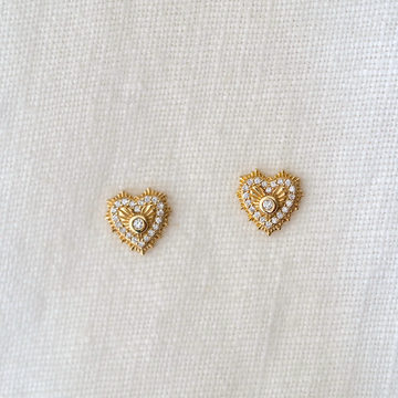 Vintage inspired hearts with a white diamond prong set at the center, radiating engraved rays outward, and an outline of white diamonds and a scalloped edge.