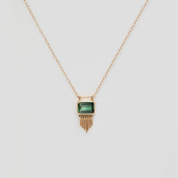 green rectangular pendant with golden fringe on gold chain on white backdrop