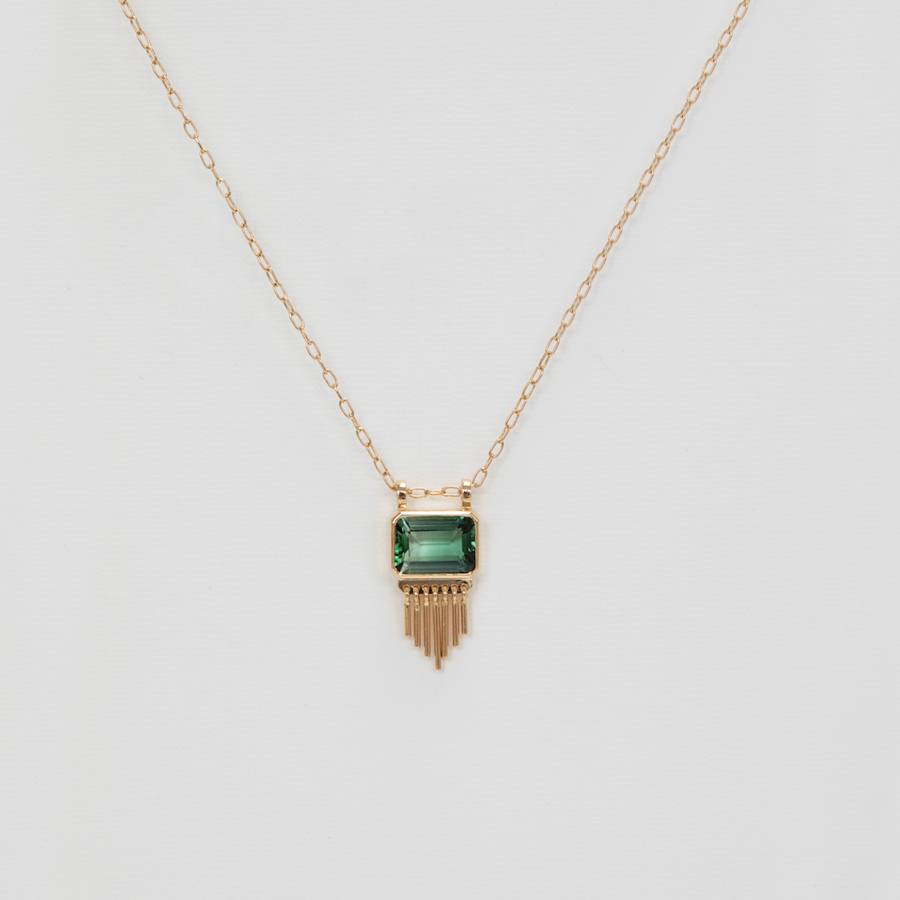 green rectangular pendant with golden fringe on gold chain on white backdrop