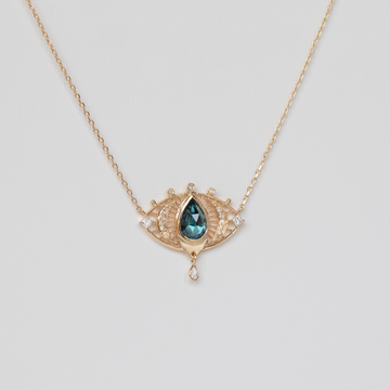 gold necklace with tourmaline pear gemstone and diamonds, on white backdrop
