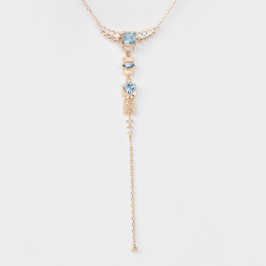 gold and aquamarine dangling lariat necklace on white backdrop