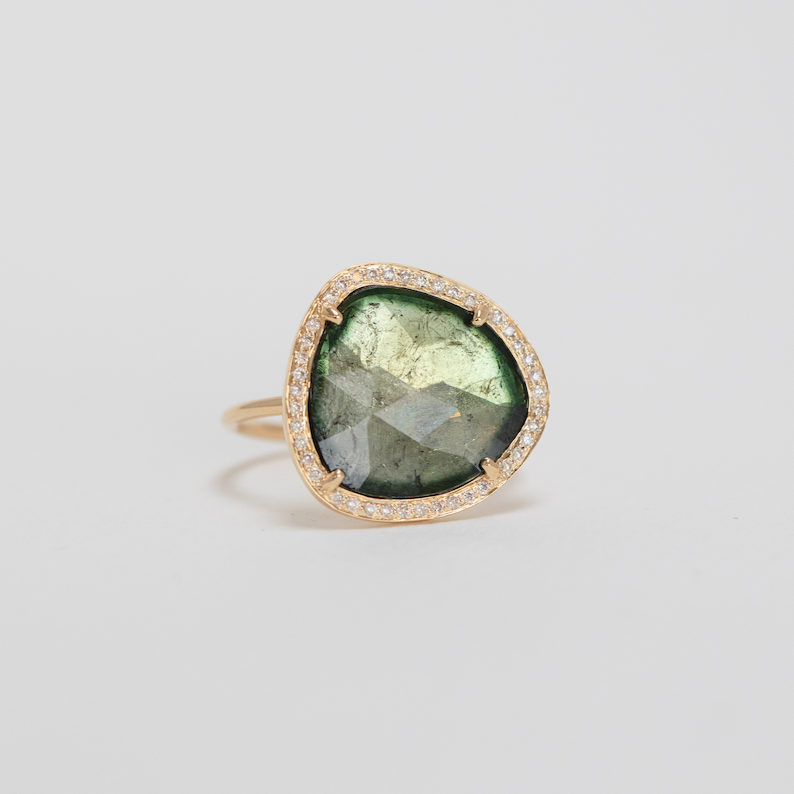 14k yellow gold ring with a unique sage green tourmaline surrounded by diamonds.