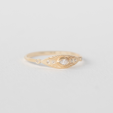 A white marquis diamond is surrounded by engraved rays in this 14k gold eye ring.