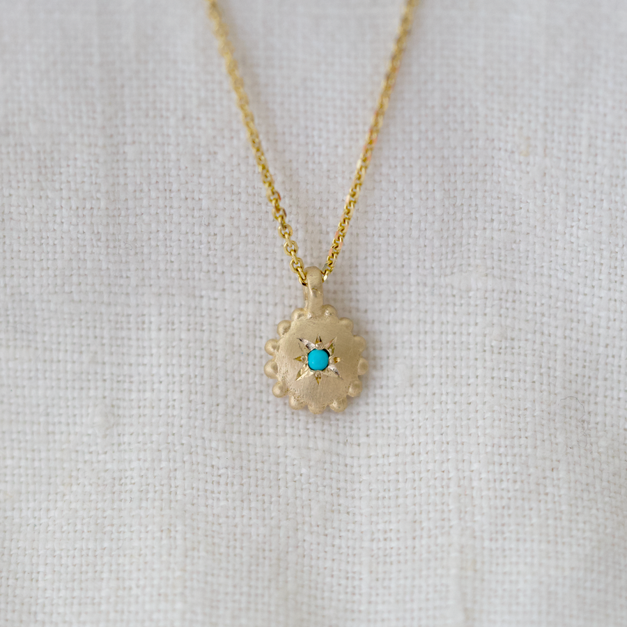 This sweet dotted pendant is bead set with a turquoise cabochon in the center