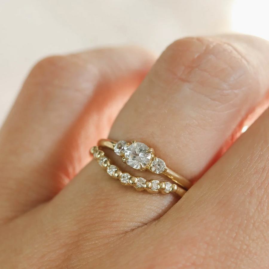 Gold ring with a diamond on a finger against a neutral background