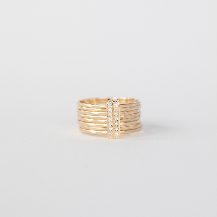 Gold ring with a diamond-studded band on a light gray background
