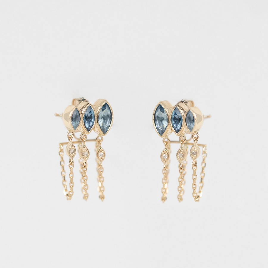 Gold earrings with blue gemstones on a light gray background