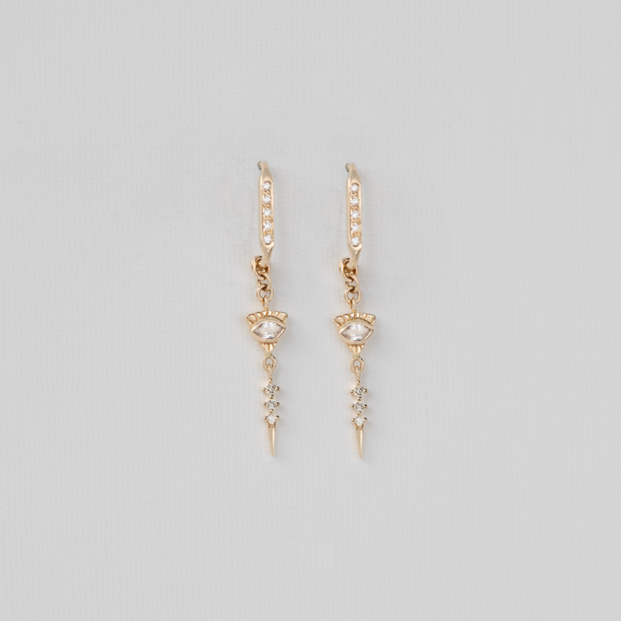 Gold earrings with small gemstones on a light gray background
