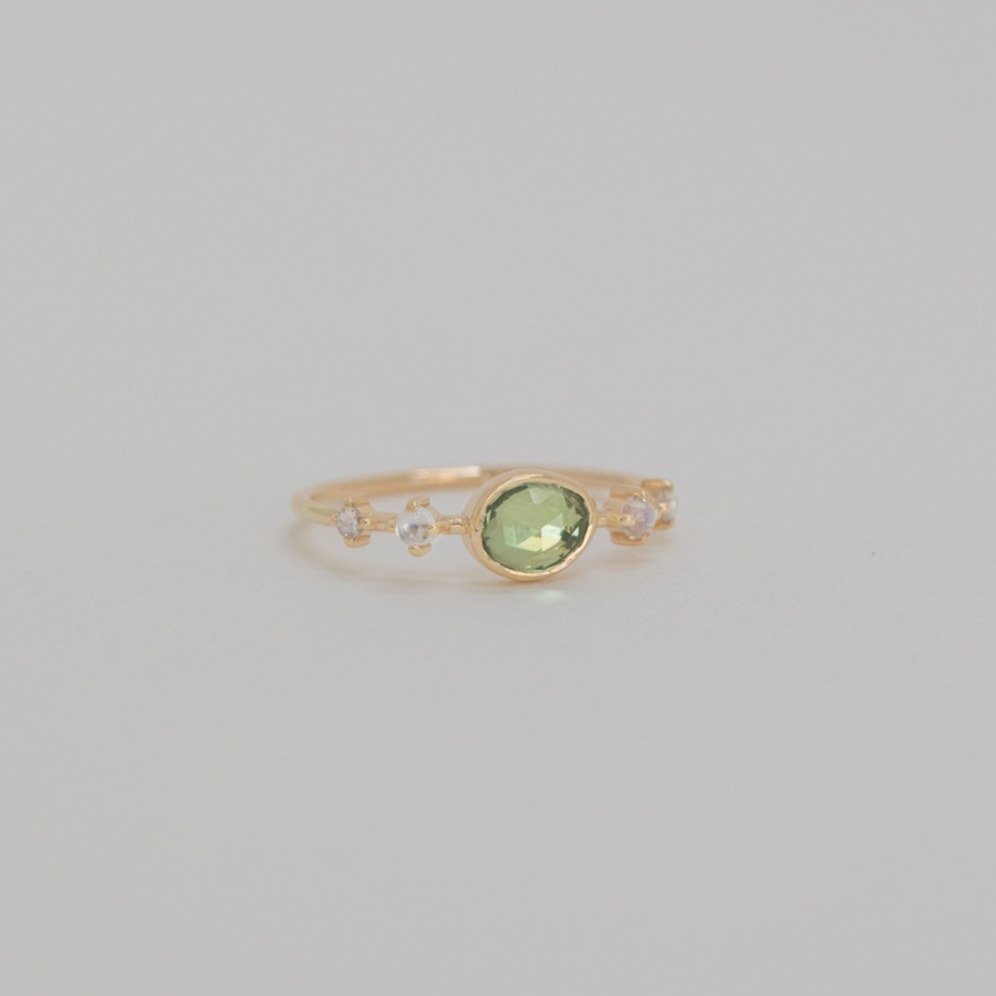 Gold ring with a green gemstone on a light gray background