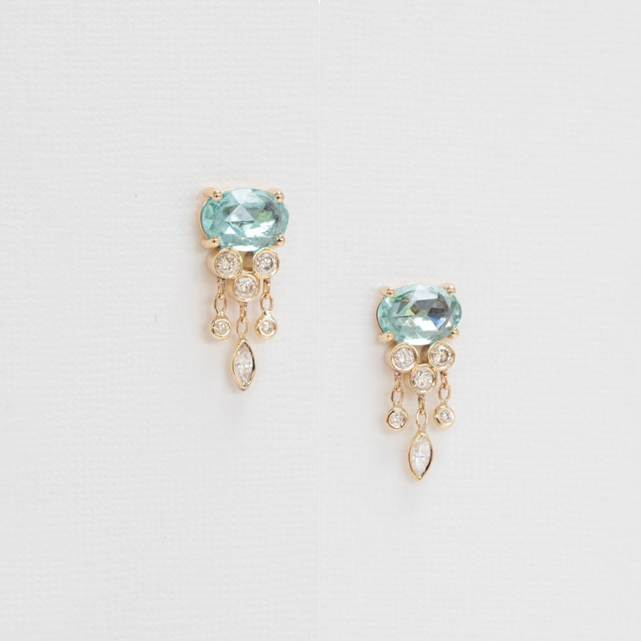 Pair of gold earrings with blue gemstones on a light gray background