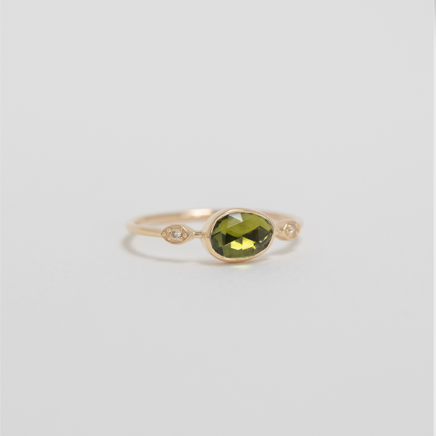Gold ring with a green gemstone on a light gray background