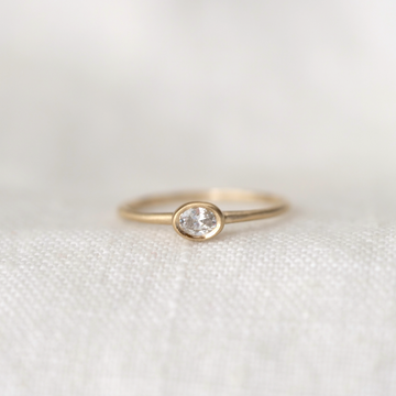 Gold ring with a diamond on a white fabric background