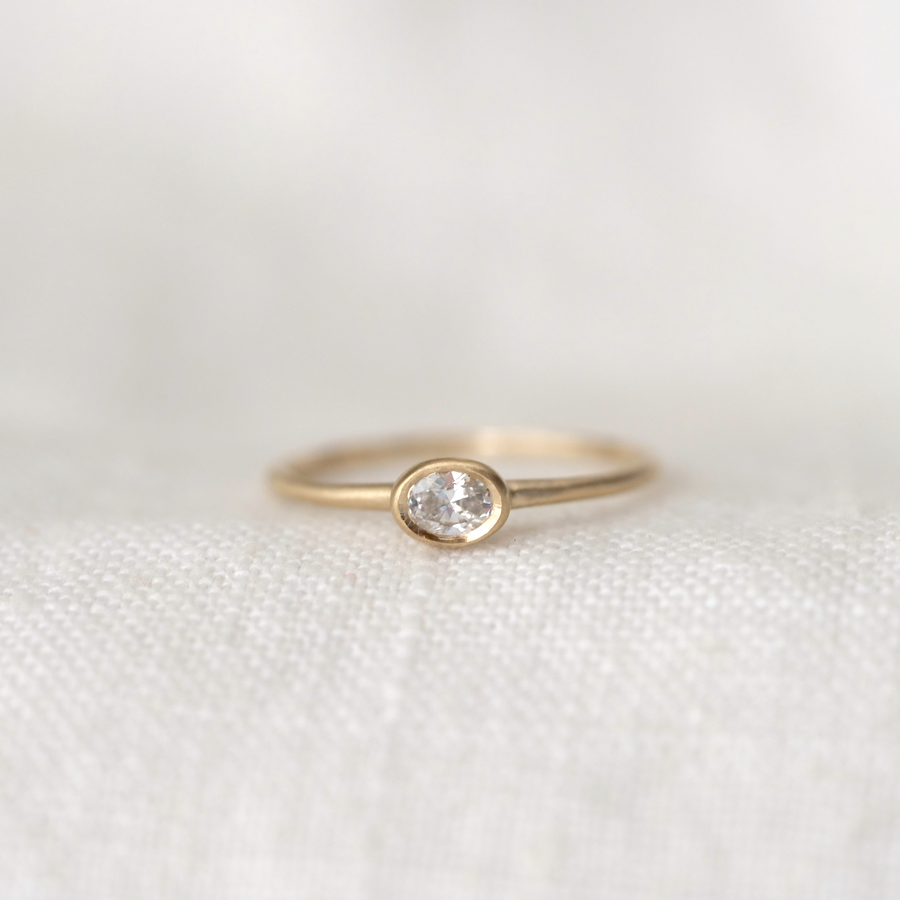 Gold ring with a diamond on a white fabric background
