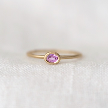 Gold ring with a pink gemstone on a white background