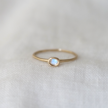 Gold ring with a moonstone on a white fabric background