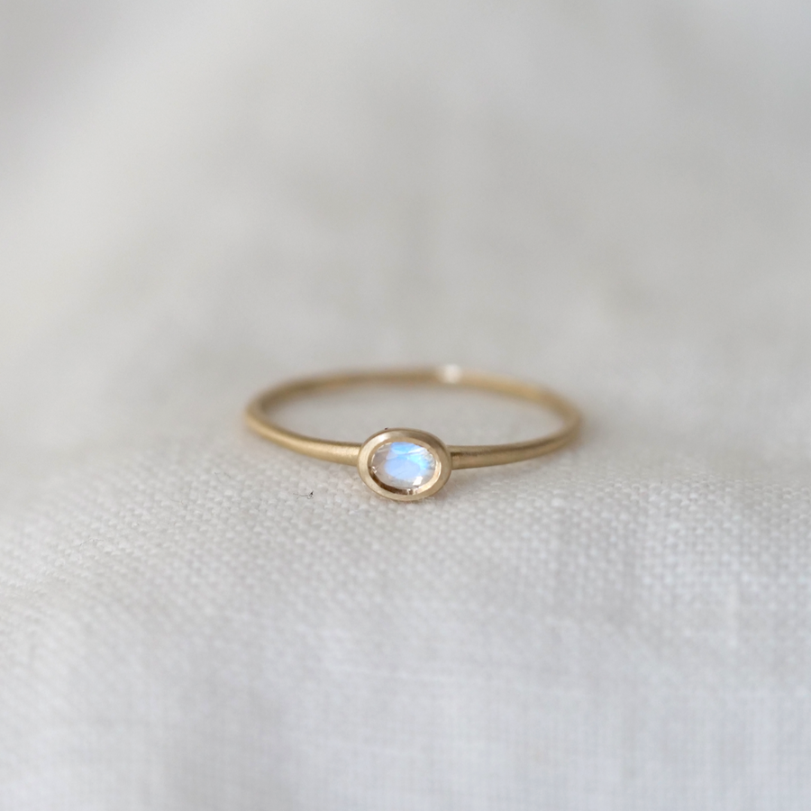 Gold ring with a moonstone on a white fabric background