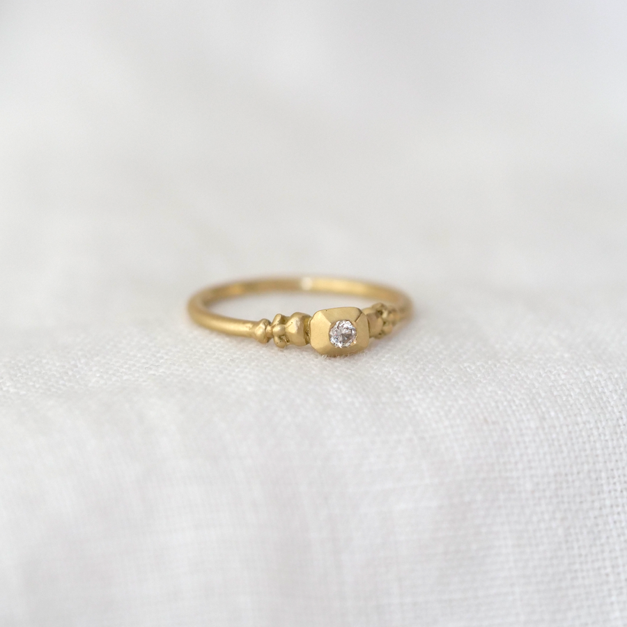 Gold ring with a diamond on a white fabric background